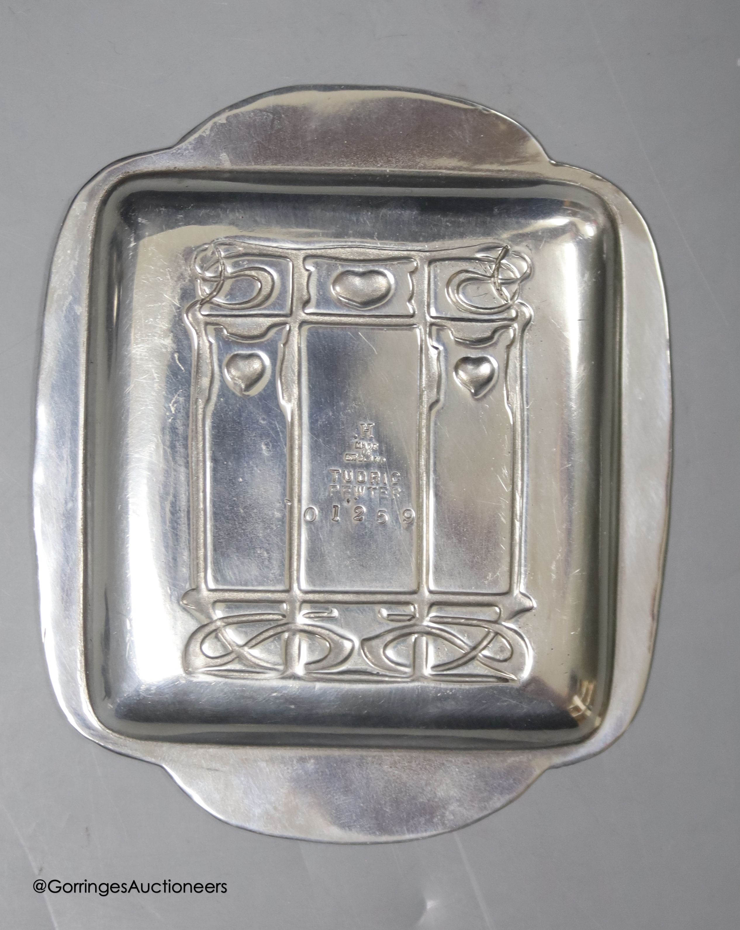 A Liberty & Co Tudric pewter pin dish, a Tudric covered jug and a pewter candleholder